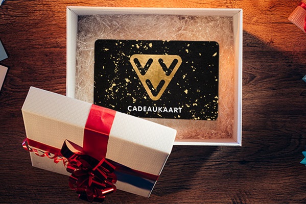 Een cadeaukaart in een open doos met rood lint, liggend op een houten tafel.