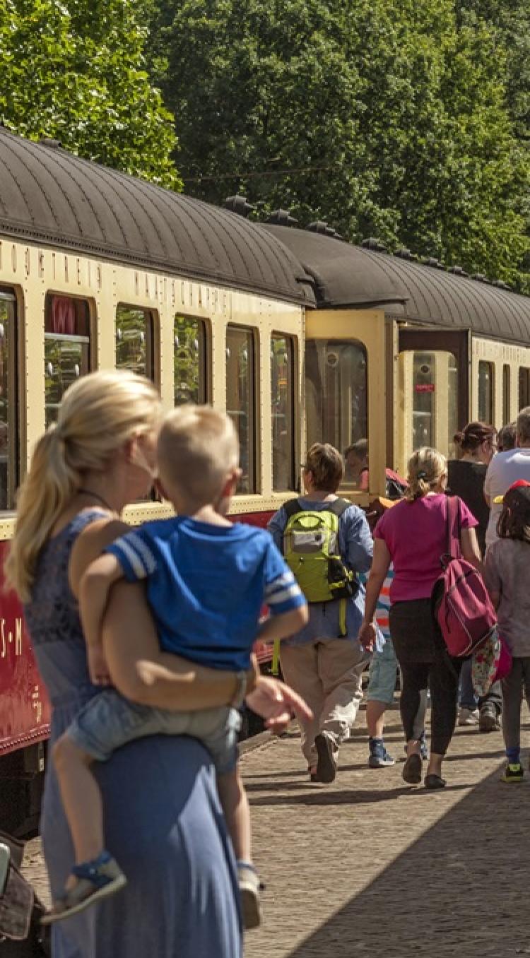 Moeder met kind en andere gezinnen wandelen langs het Miljoenenlijntje tijdens een van de populaire familie-uitjes in Limburg.